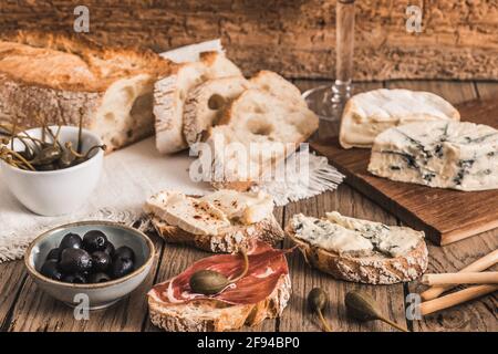 Pain blanc croustillant avec bacon et fromage et un bol avec olives sur table rustique en bois Banque D'Images