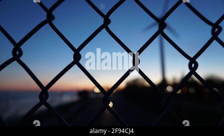 L'horizon de la ville visible depuis l'arrière des fils. Lumières et câbles de la ville en soirée. Bokeh derrière les clôtures. Banque D'Images