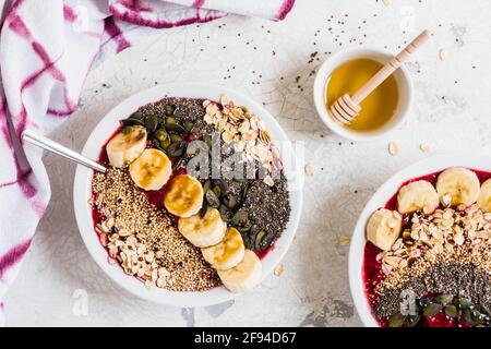 Petit déjeuner sain. Bols à smoothie avec bleuets, banane, flocons d'avoine, graines de chia, quinoa, graines de citrouille et miel. Vue de dessus. Banque D'Images