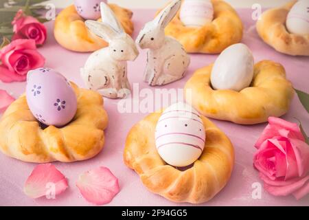 Petits pains de pâques faits maison avec œufs de pâques colorés sur fond rose Banque D'Images