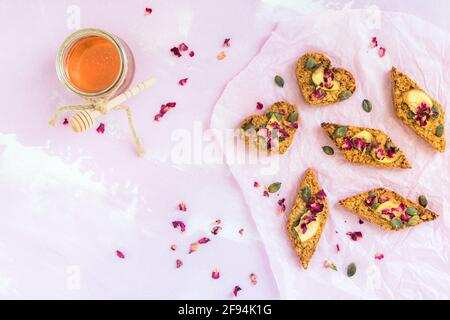 Barres de muesli aux pommes faites maison, décorées de graines de pomme et de citrouille séchées, sur fond rose pâle, vue du dessus Banque D'Images