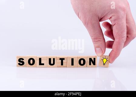 Solution de mot orthographié à partir de lettres de dés, main mettant ampoule icône cube Banque D'Images