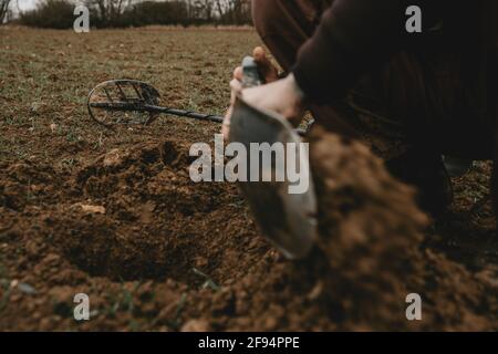 Détail des mains de l'homme avec une pelle dans celle-ci, lors de l'excavation d'un trou dans le sol après le signal positif du détecteur de métal Banque D'Images