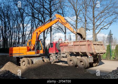 Sol en mouvement du Digger. Travaux de pelle hydraulique sur le chantier au coucher du soleil. Travaux de terrassement. La pelle rétro jaune creuse le sable Banque D'Images