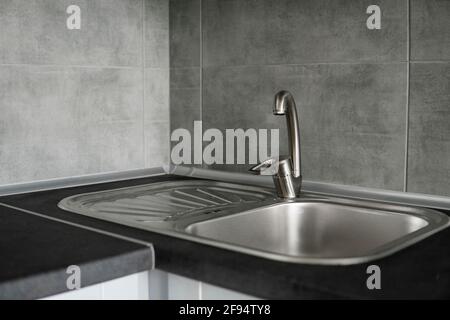 Évier de cuisine en acier inoxydable sur un plan de travail en granit gris foncé. Évier de cuisine et robinet d'eau dans la cuisine. Banque D'Images