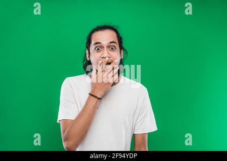 Portrait d'un jeune homme avec de longs cheveux noirs avec une expression faciale choquée Banque D'Images