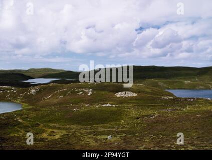 Voir NW montrant Punds Water le cairn néolithique en forme de talon situé sur un chevalier rocheux entre les loches du nord du continent, Shetland, Écosse, Royaume-Uni. Banque D'Images