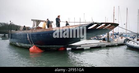 AJAXNETPHOTO. 1993. HAMBLE RIVER, ANGLETERRE. - GRAND CLASSIQUE DE CLASSE - LA COQUE DU YACHT LULWORTH (EX TERPSICHORE) QUI AVAIT ÉTÉ AMARRÉ À CRABLECK UTILISÉ COMME PÉNICHE PAR LE MARI ET LA FEMME RICHARD ET RENE LUCAS PENDANT DE NOMBREUSES ANNÉES, ÉTANT REMORQUÉ POUR LA RESTAURATION PAR DE NOUVEAUX PROPRIÉTAIRES À VIAREGGIO, ITALIE. YACHT A ÉTÉ CONSTRUIT COMME GRANDE CLASSE GAFF-TRUGGED CUTTER PAR LES FRÈRES BLANCS, ITCHEN FERRY EN 1920 CONÇU HERBERT WILLIAM BLANC. PHOTO:JONATHAN EASTLAND/AJAX. REF:1993 9A 22 Banque D'Images