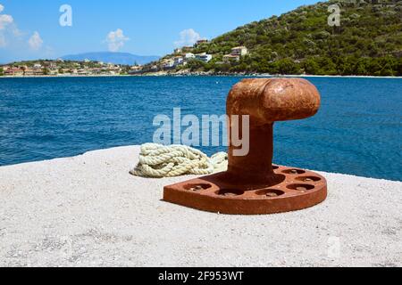 Vieux bollard d'amarrage rouillé avec cordes navales sur la jetée en béton. Grèce. Corfou. Banque D'Images