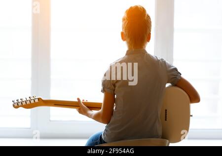 Silhouette d'une belle jeune fille avec une guitare près de la fenêtre. Banque D'Images