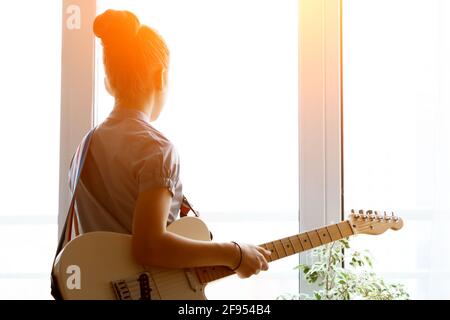 Silhouette d'une belle jeune fille avec une guitare près de la fenêtre. Banque D'Images