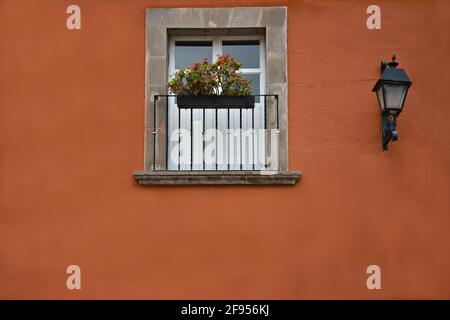 Maison coloniale mur en stuc vénitien rouge avec une fenêtre en pierre et un balcon en fer fait à la main à Santiago de Querétaro, Mexique. Banque D'Images