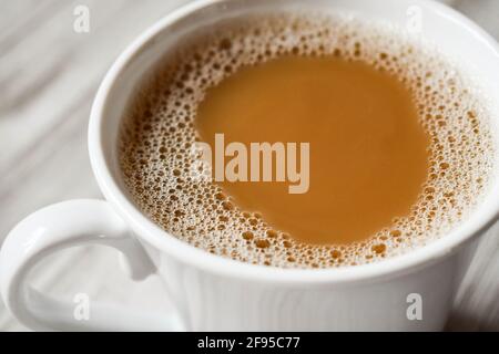 Café fraîchement préparé avec de la crème dans une tasse blanche sur fond de bois, vu d'en haut Banque D'Images