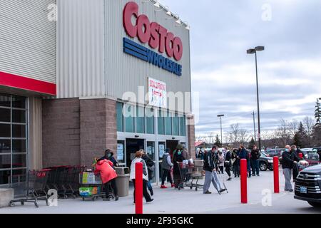 London, Ontario, Canada - 7 2021 mars : les foules quittent Costco au pays des merveilles, portant des masques médicaux tandis que d'autres font la queue pour entrer et faire des achats. Banque D'Images