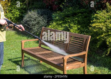 Homme nettoyant banc de jardin en bois avec un nettoyeur haute pression au printemps. Banque D'Images