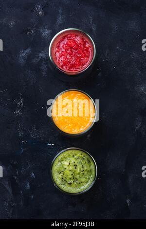 Orange sicilien, Tangerine et Kiwi Smoothie.les verres sont disposés dans l'ordre des couleurs des feux de circulation Banque D'Images