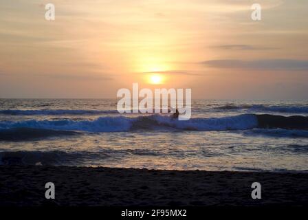 Surfer au coucher du soleil. Legian Beach, Pantai Legian, Bali, Indonésie. Bali est un endroit populaire de surf avec de nombreuses écoles de surf. Près de Kuta et Seminyak. Banque D'Images