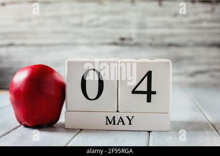 Blocs de calendrier en bois blanc avec la date du 4 mai et une pomme rouge pour la Journée nationale d'appréciation des enseignants. Banque D'Images