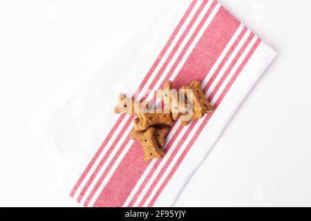 Vue de dessus de pile de biscuits bruns pour chiens sur rouge et serviette de cuisine blanche Banque D'Images