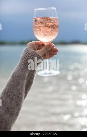 verre rempli de vin rose dans la main de la fille, pique-nique sur la plage Banque D'Images