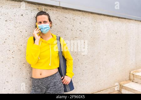 Femme active avec vêtements de sport et tapis parlant au téléphone Banque D'Images