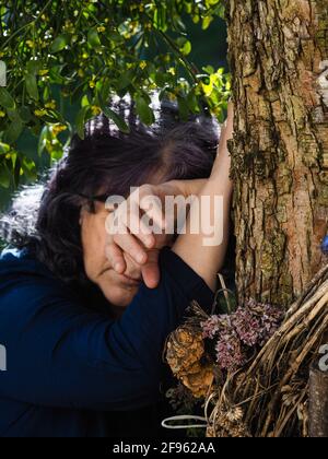 Femme adulte sénior près d'un arbre aimé et d'une plante de GUI Banque D'Images