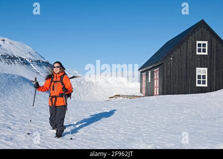 femme qui part pour une randonnée depuis le chalet de ski Islande Banque D'Images