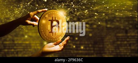 Homme d'affaires tenant une pièce d'or Bitcoin avec arrière-plan numérique binaire. Concept de technologie de crypto-monnaie et de blockchain. Banque D'Images