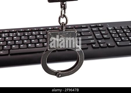 Menottes de police et clavier d'ordinateur sur fond blanc. Banque D'Images