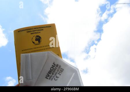 Munich, Allemagne. 16 avril 2021. Illustration - UN livre de vaccination et un masque de protection FFP2 peuvent être vus contre un ciel bleu-blanc. Credit: Felix Hörhager/dpa/Alay Live News Banque D'Images