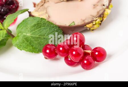 Délicieux foie gras recouvert de chocolat noir et de pistaches de confiture de baies rouges et de menthe. Macro. La photo peut être utilisée comme arrière-plan entier. Banque D'Images