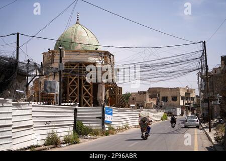 Un homme à moto près de la mosquée Al-Nuri. La mosquée Al-Nuri a été construite en 1,172 et qui comprend également le minaret Al-Hadba, est actuellement en cours de reconstruction dans son ancienne conception par l'UNESCO après qu'elle ait été détruite pendant la guerre contre l'EI (État islamique d'Irak et de Syrie). La mosquée a une signification symbolique pour l'EI, comme son chef, Abu Bakr al-Baghdadi, a déclaré le soi-disant califat de l'intérieur de la mosquée. Banque D'Images