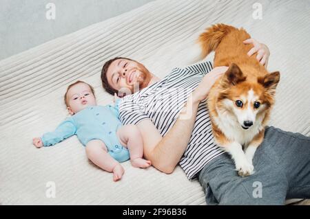 Papa et son fils sont couchés sur le lit avec le chien. Portrait en gros plan Banque D'Images