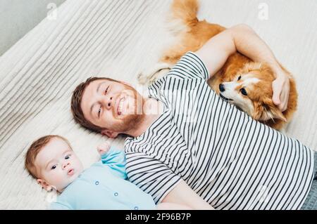 Papa et bébé sont couchés sur le lit avec le chien. Portrait en gros plan Banque D'Images