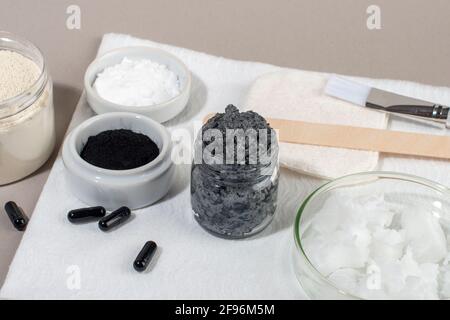 Ingrédients pour un masque facial au charbon de bois maison. Poudre de charbon de bois, huile de coco, argile cosmétique blanche. Concept beauté maison. Banque D'Images