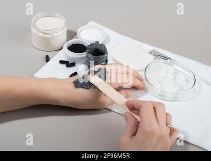 Les mains des femmes testent le masque facial au charbon de bois sur la peau de la main. Gros plan. Concept beauté maison. Banque D'Images