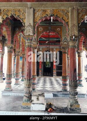 Varanasi, Inde - 01 novembre 2016 : intérieur d'un ancien temple hindou vide avec un design sculpté en pierre, piliers avec sol en marbre de damier et cloche sw Banque D'Images