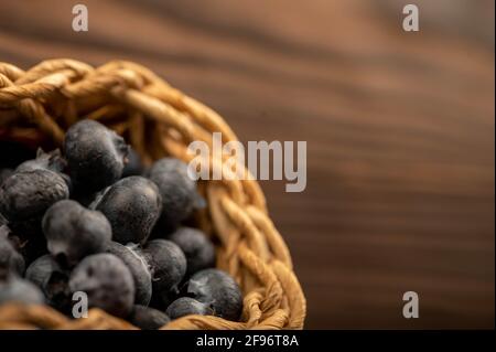 Bleuets frais dans un panier en osier sur une table en bois. Récolte, petit déjeuner du village. Mise au point sélective en gros plan. Banque D'Images