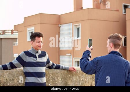 Jeune homme prenant des photos de son ami à l'extérieur Banque D'Images
