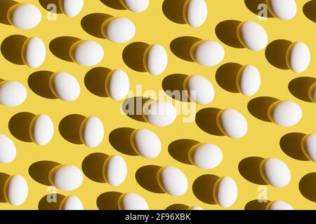 Motif sans couture avec œufs blancs et ombres d'été tendance sur fond jaune. Concept de Pâques ou de nourriture minimal. Pose à plat. Banque D'Images