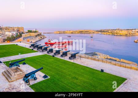 Vue sur le coucher du soleil de la batterie saltante en face de la ville de Birgu avec fort St. Angelo et Senglea à la Valette, Malte Banque D'Images
