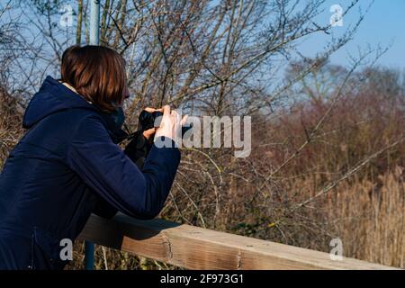 Femme avec des jumelles observant les oiseaux dans le lagon de Marano Banque D'Images