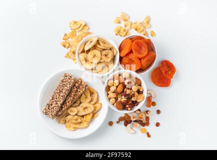 Barre de granola, noix et fruits secs sur fond clair avec des assiettes blanches. Vue de dessus, horizontale. Bonbons naturels et sains. Banque D'Images