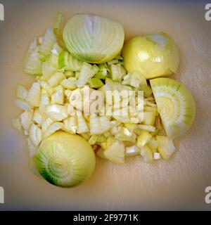 bulbes d'oignon blanc coupés en deux, morceaux d'oignon hachés et ail sur une planche à découper en plastique Banque D'Images
