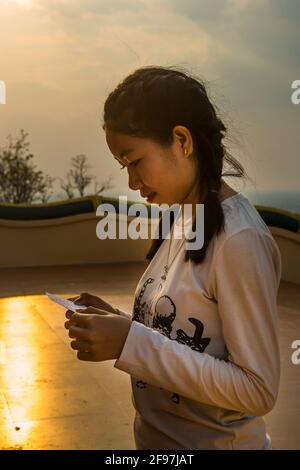 Laos, Pakse, le temple Vat Phou Salao, femme jeune, lire, profil, Banque D'Images