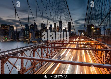 Photo en exposition prolongée du pont de Brooklyn à New York, États-Unis à l'aube avec des bandes claires floues des voitures qui se précipitent Banque D'Images