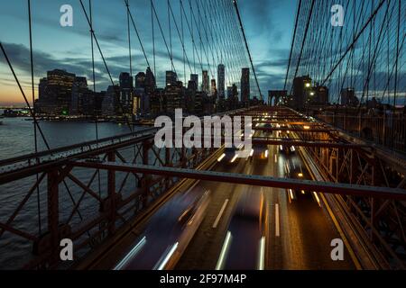 Photo en exposition prolongée du pont de Brooklyn à New York, États-Unis à l'aube avec des bandes claires floues des voitures qui se précipitent Banque D'Images