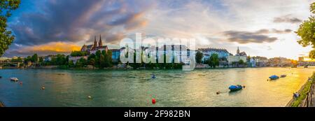 Vue au coucher du soleil sur le bord du Rhin à Bâle dominée par le majestueux bâtiment de l'église Munster, Suisse Banque D'Images