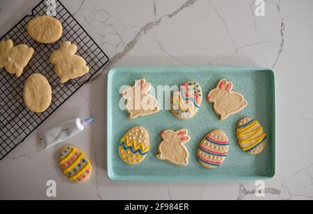Plateau de biscuits de Pâques décorés sur un comptoir blanc tiré par le dessus. Banque D'Images