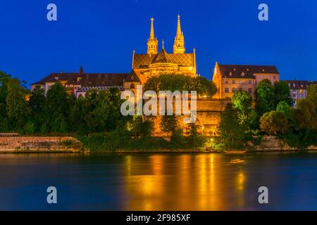 Vue au coucher du soleil sur le bord du Rhin à Bâle dominée par le majestueux bâtiment de l'église Munster, Suisse Banque D'Images